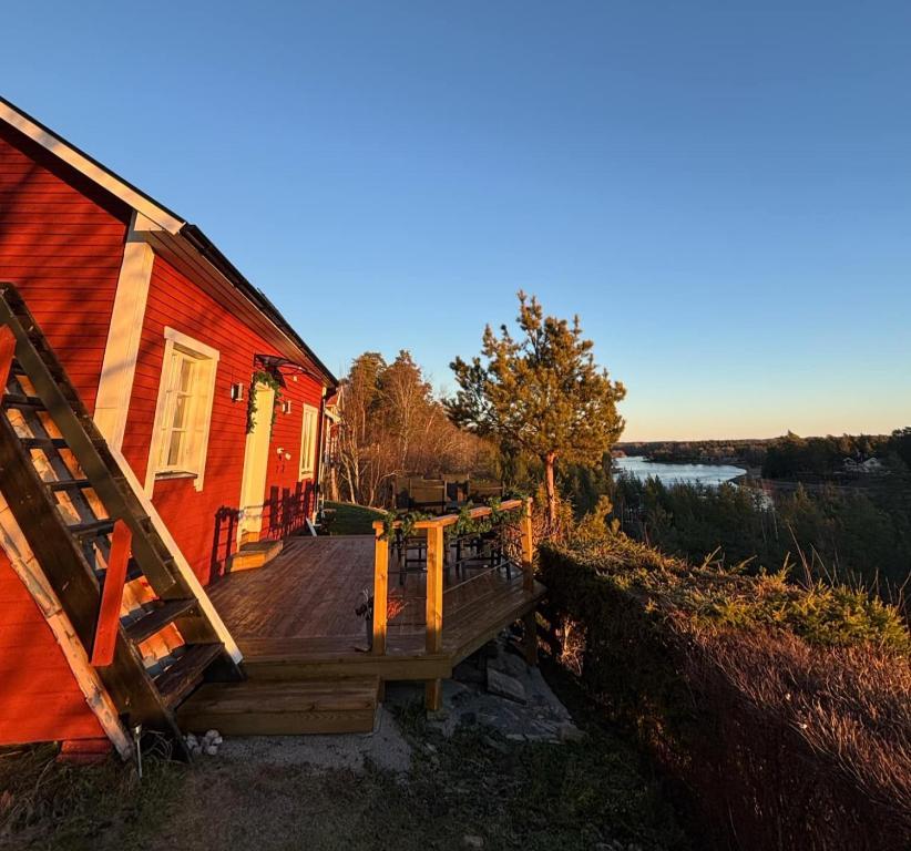 Red cottage with wooden terrace at sunset overlooking the Dalälven river